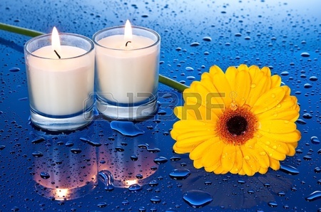 bloem bij kaarslicht met een reflectie op blauwe ondergrond